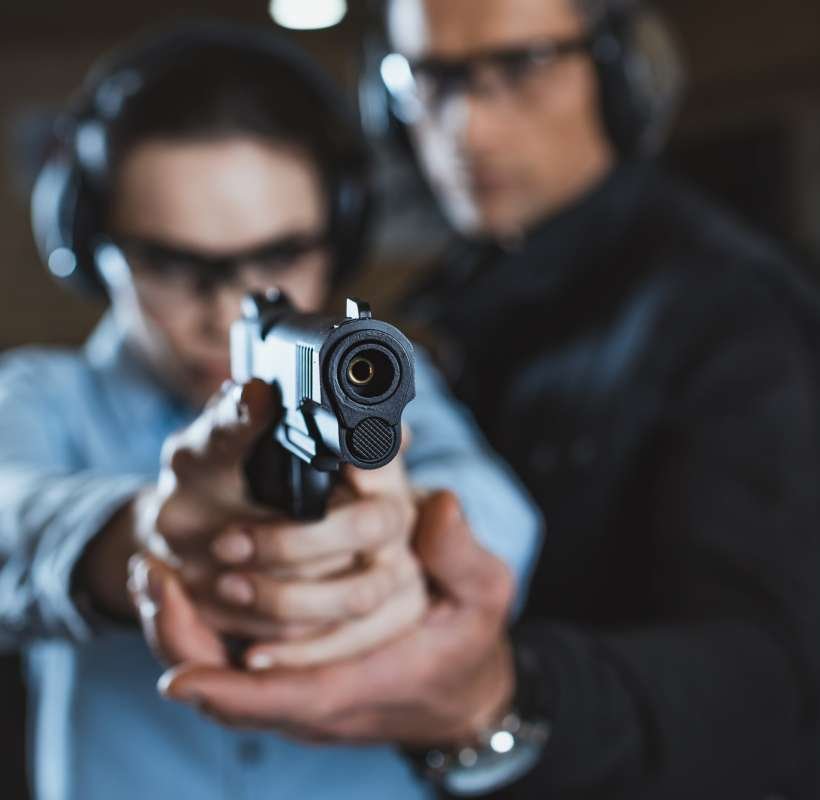 instructor-helping-customer-in-shooting-gallery-with-gun-on-foreground.jpg